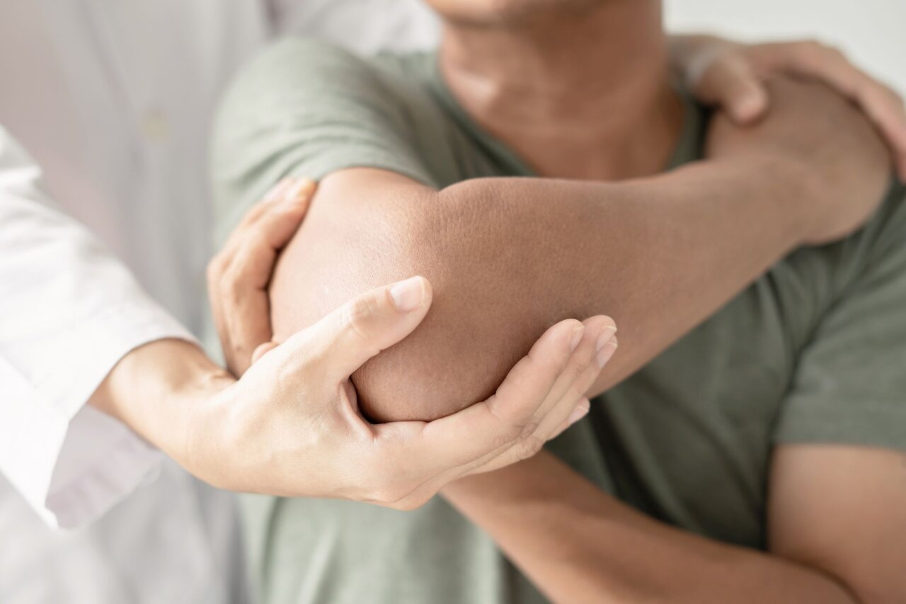 Therapeutin mobilisiert den Ellenbogen eines Patienten – typische physiotherapeutische Maßnahme zur Behandlung von Gelenkbeschwerden und Bewegungseinschränkungen.