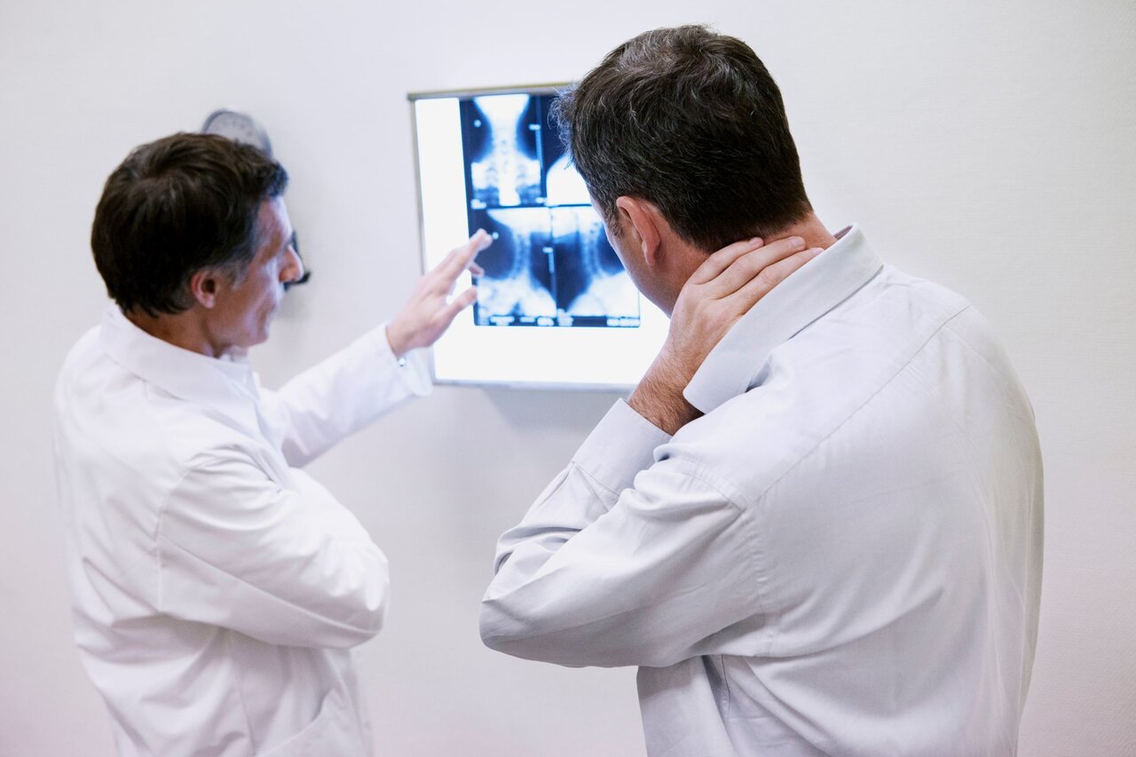 Arzt zeigt Patient MRT-Aufnahmen der Wirbelsäule – Diagnostik bei Nackenschmerzen zur Abklärung möglicher Ursachen wie Bandscheibenvorfall oder Arthrose.