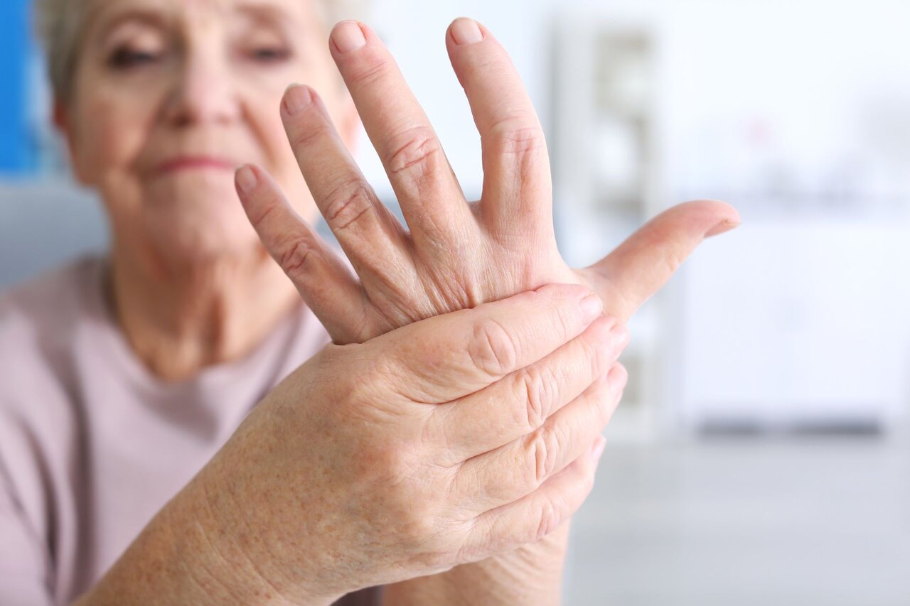Ältere Frau hält schmerzende Hand bei rheumatischer Arthritis.
