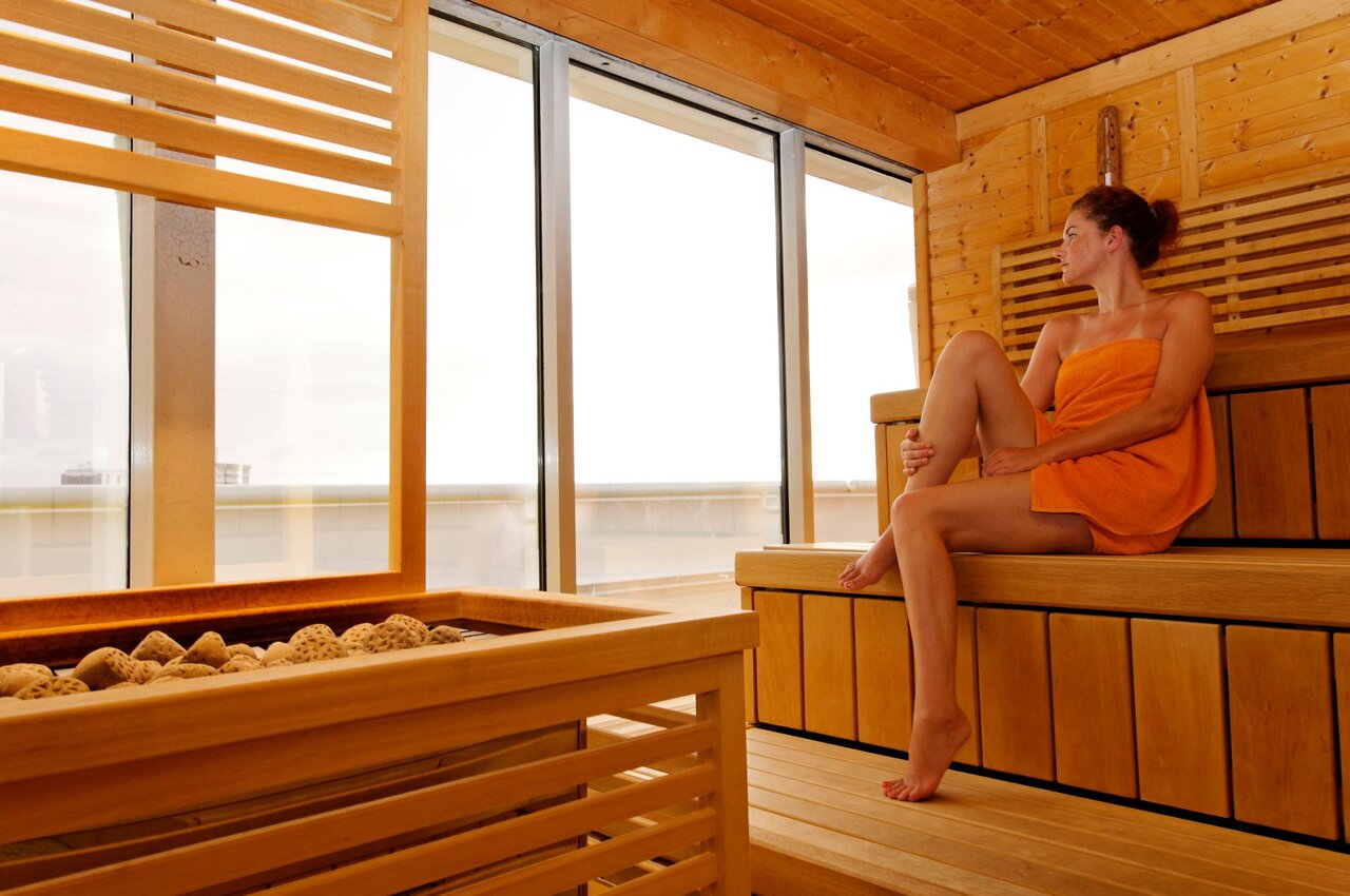 Frau mit Muskelkater entspannt sich in der Sauna – Wärme unterstützt die Regeneration beanspruchter Muskeln.