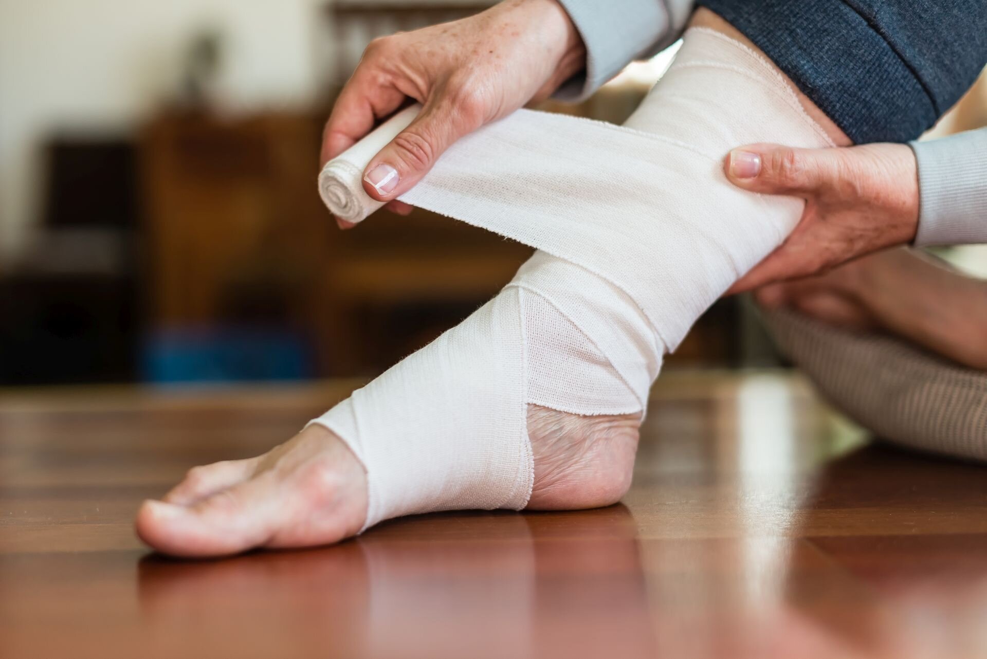 Mit elastischem Verband bandagierter Fuß nach Prellung auf Holzboden