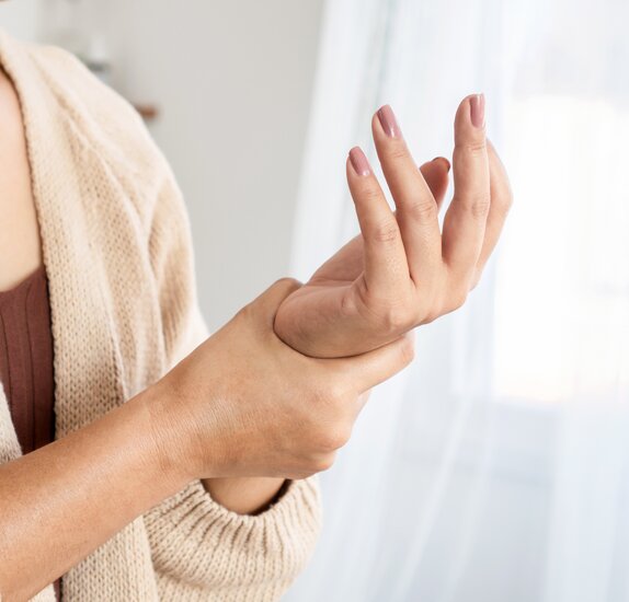 Frau mit Rheuma an der Hand